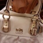 Cream and white Coach bag with gold hardware.